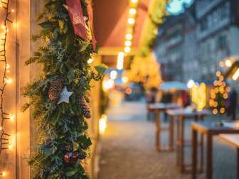 Ein Holzstand ist weihnachtlich geschmückt. Im Hintergrund erkennt man verschwommen die Steiner Altstadt.