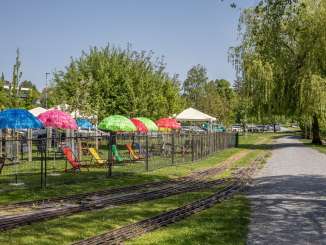 Luusbuebe Bar Stein am Rhein A pop-up bar has been set up on a meadow in a park. Colorful deckchairs and umbrellas have been set up.