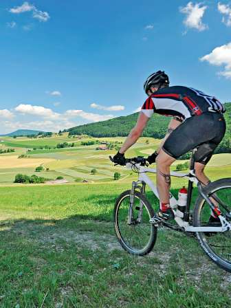 Three mountain bikers ride down a small hill on a narrow path.