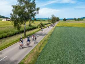 slowUp Schaffhausen-Hegau Many cyclists are riding on a road that is closed to cars. The road runs alongside a stream and fields.