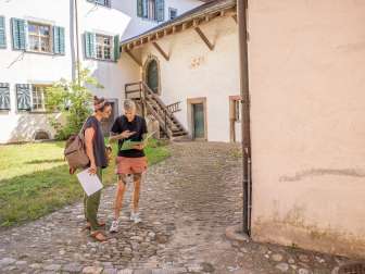 Treasure hunt Neunkirch Two friends stand in a courtyard and solve a riddle.