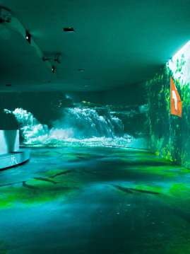 A room with various projectors. The walls are illuminated with water images.