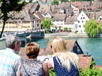 Guided tour of Stein am Rhein Three people look closely at a map. The Rhine and the old town of Stein can be seen in the background.