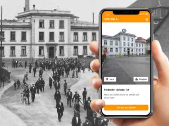 Explorial Neuhausen am Rheinfall A hand holds a cell phone in front of a black and white picture. On the cell phone you can see the building as it looks today.