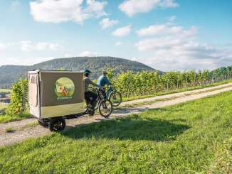 Two friends are out and about in the vineyards on their e-bikes. A Cargovelo has a fold-out tent structure.