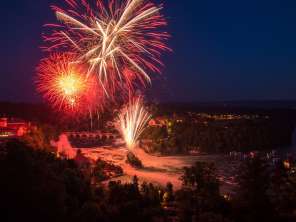 A large red firework is lighting up the sky above the Rhine Falls.