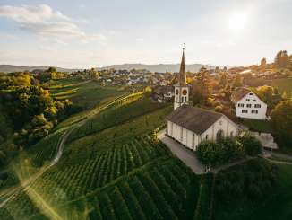 A view of the Buchberg  Rüdlingen church Rüdlingen vineyards in the golden evening light. A village can be seen in the background.