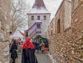 Medieval market Schloss Laufen at the Rhine Falls A person in medieval garb and a red cap walks through the castle courtyard. Market stalls stand at the edge.