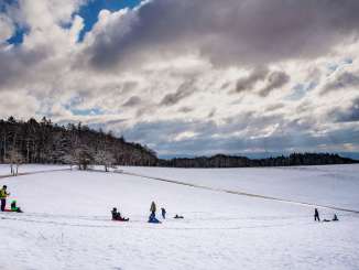 Tobogganing on the Randen Several families are sledging down a small snow-covered hill. The edge of the forest can be seen in the background.