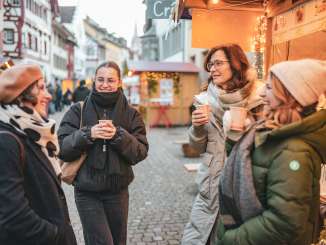 steinamrhein-maerlistadt-december-winter (9) Four women at a Christmas market with a mug of mulled wine in their hands.