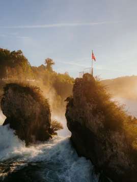 Rhine Falls in fall View from behind of the two rocks in the middle of the waterfall. Goldie's light shines on the waterfall.