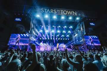 Concert with a large stage and a large audience as well as spotlights with blue light.